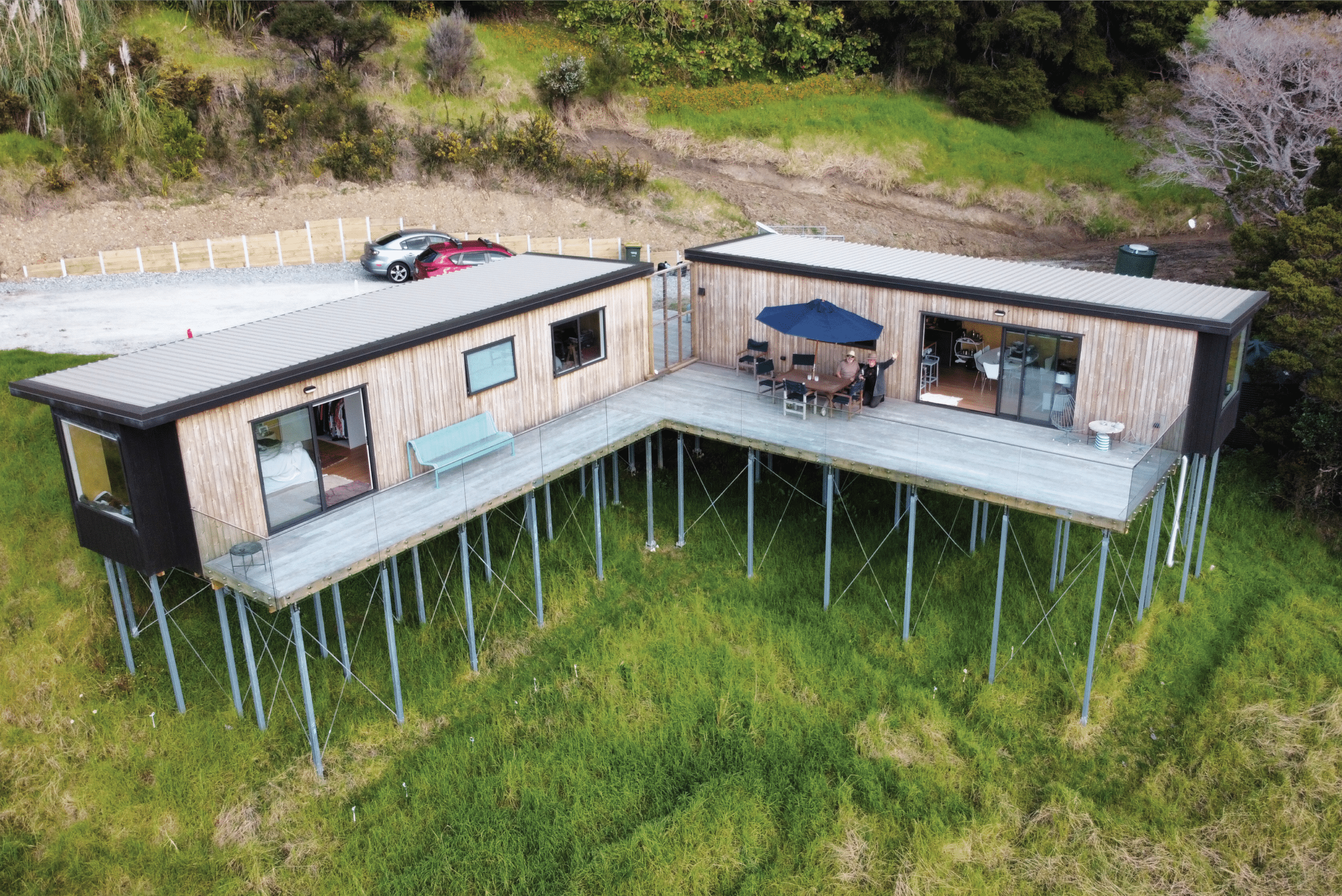 Photo of a man and his father on a deck looking at a drone as it captures photo of two ecopods side by side. 