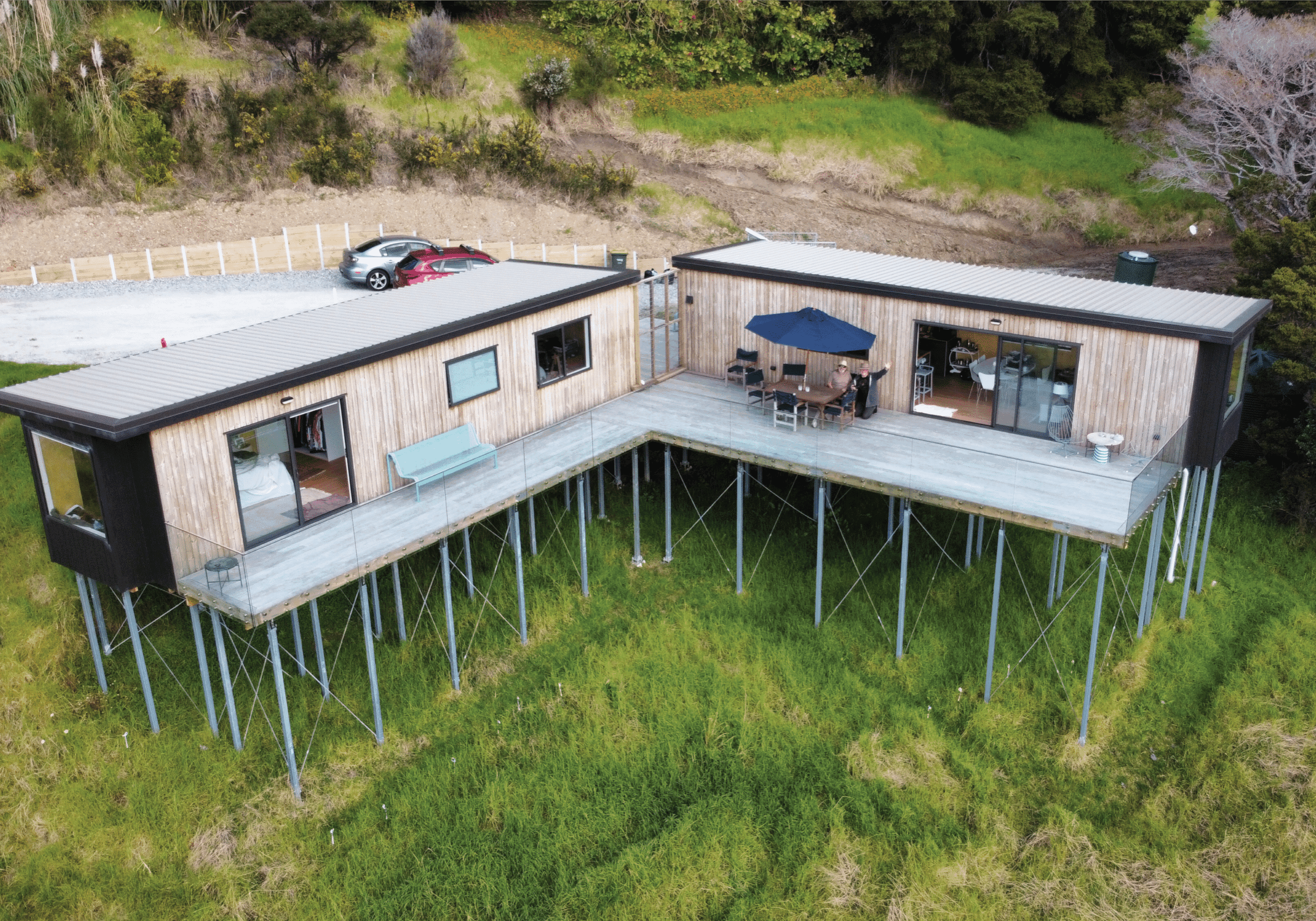 Photo of a man and his father on a deck looking at a drone as it captures photo of two ecopods side by side. 